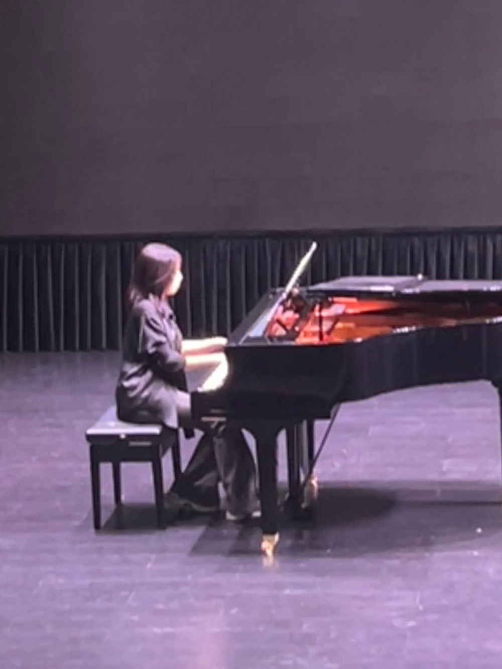 young woman playing a piano on stage