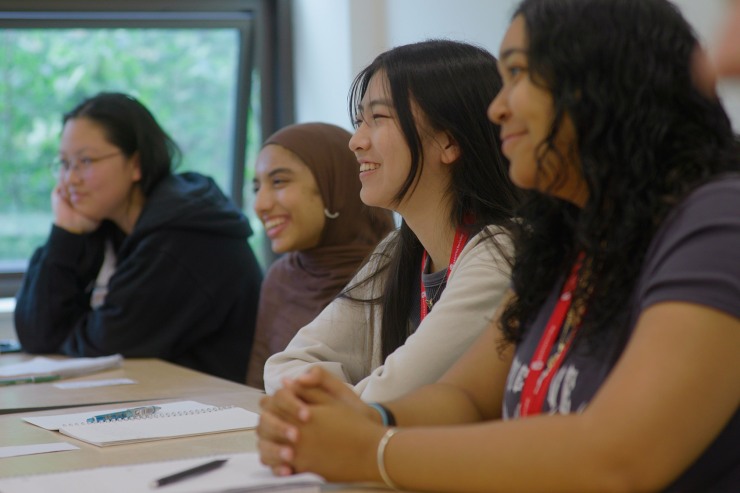 Students sitting at a table in a classroom, smiling