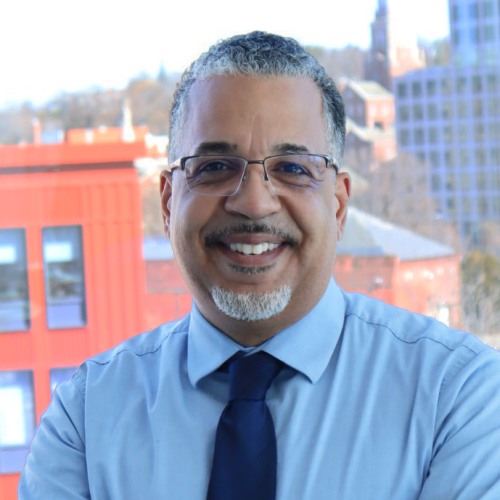 Headshot of Nick Figueroa standing in front of a window overlooking downtown Providence