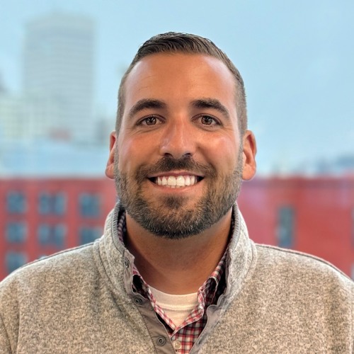 Headshot of Zach Pelletier standing in front of a window overlooking downtown Providence