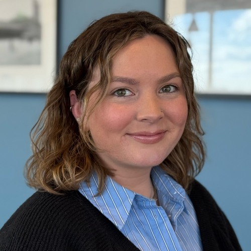 Headshot of Lucy Small wearing a black sweater in front of a blue wall