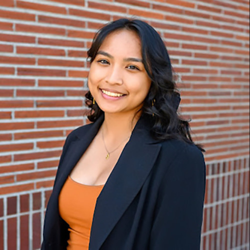 Headshot of Victorya Esperanza in front of a red brick wall