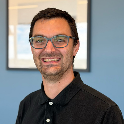 Photo of Kevin Coccio standing in front of a blue wall