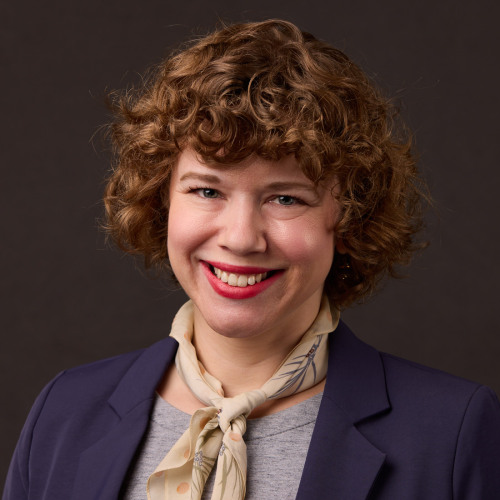 Headshot of Katie Stewart smiling in front of a black backdrop