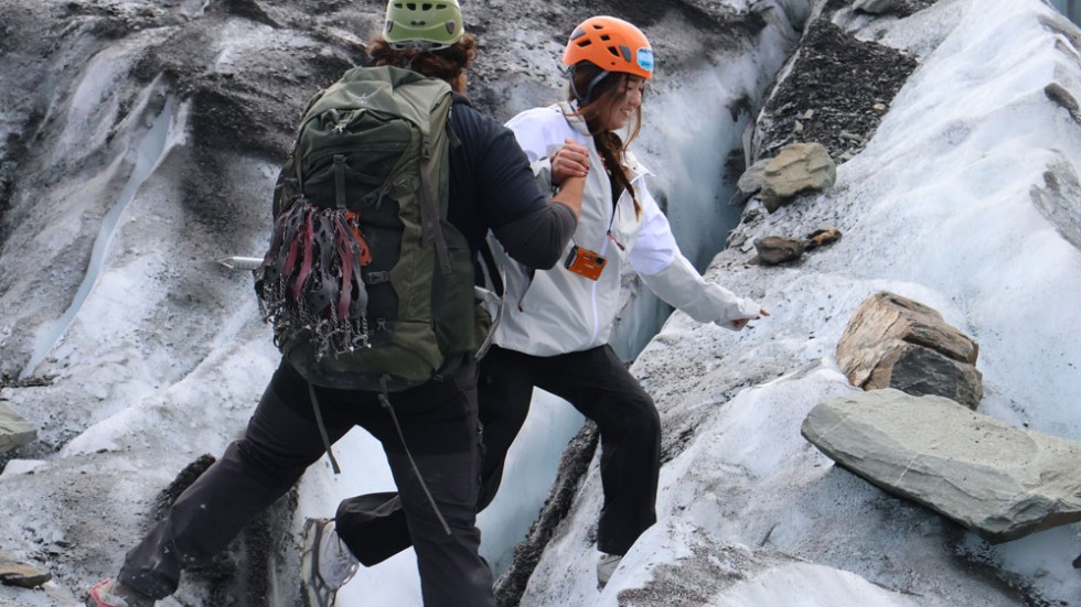 Instructor assisting a student while hiking on an icy surface