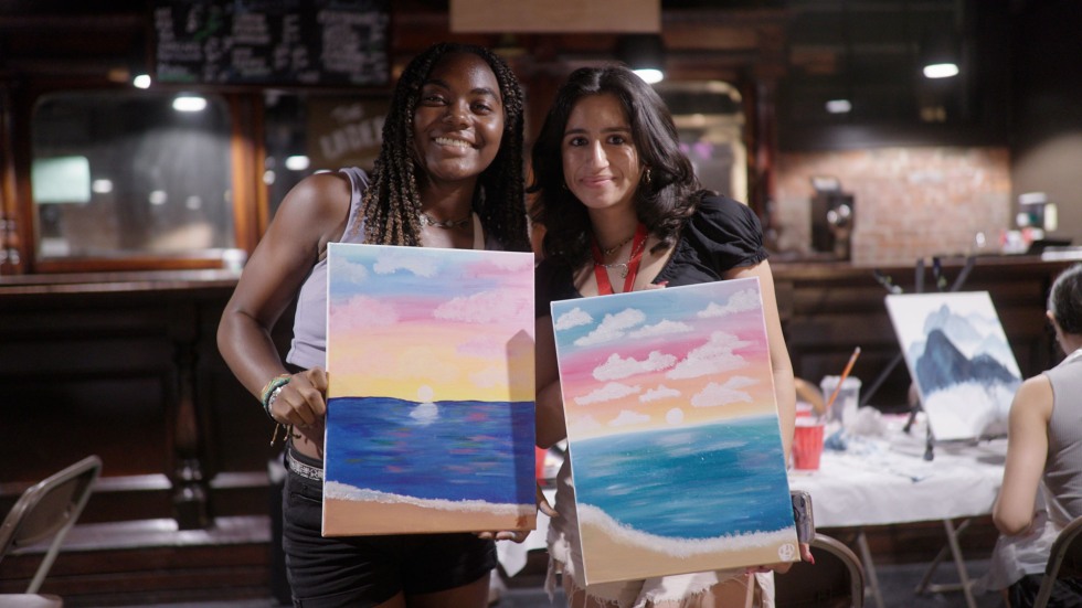 two girls posing with the canvas they just painted