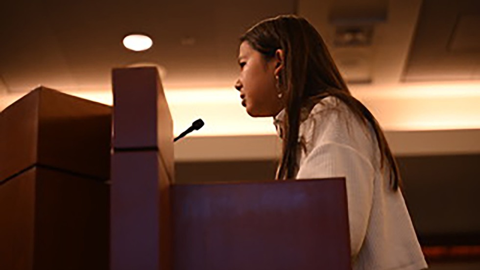 Side view of a girl giving a speech at a podium