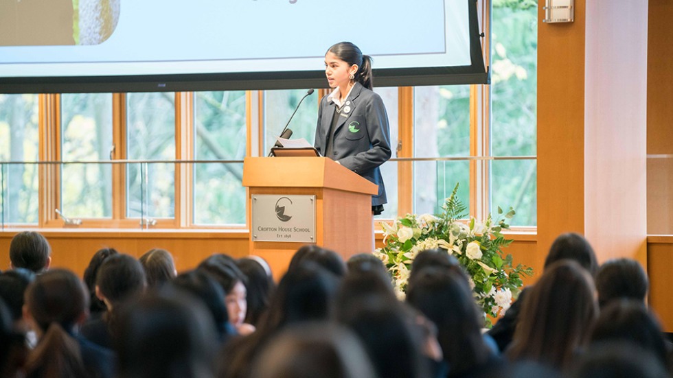 Young woman standing at a podium giving a speech to a crowd