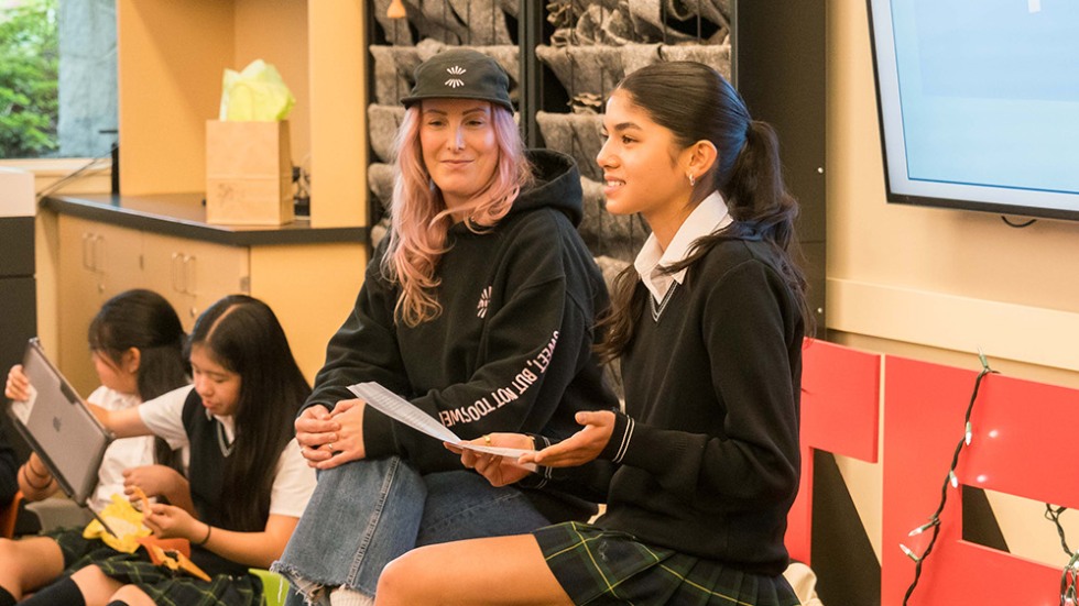 Two women sitting in chairs holding a discussion panel
