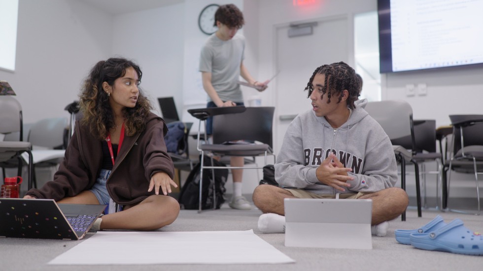 two students sitting on the floor working on a project
