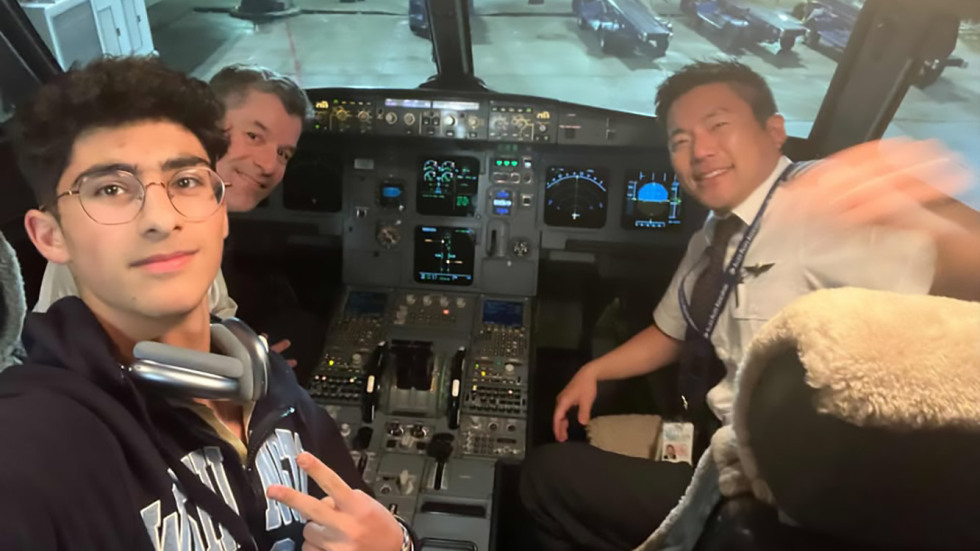 Yusuf posing with two pilots in a plane cockpit