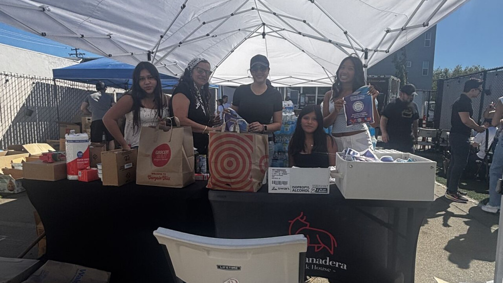 People standing behind a table full of donation items