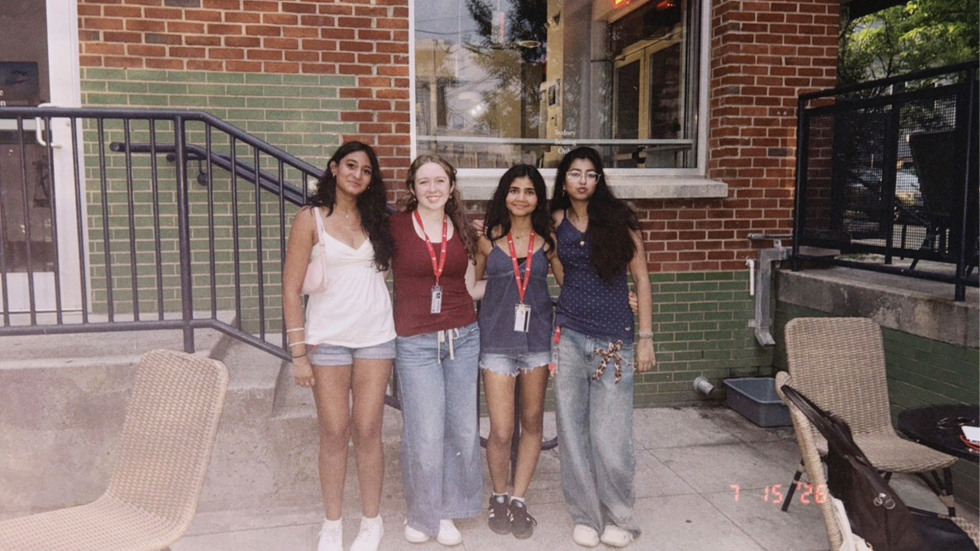 Four teen girls standing together in front of a building