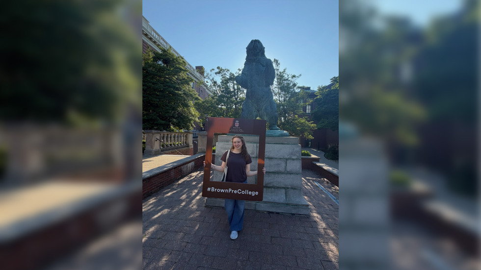 Ella standing in front of the Brown University Bruno statue with a selfie frame